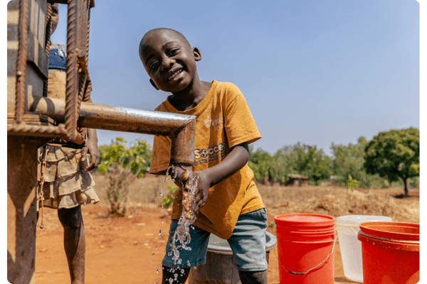 Smiling Malawi child drinks water from a borehole